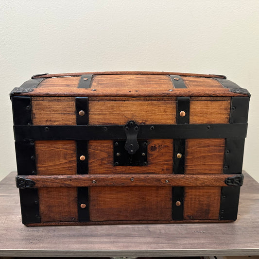 Wooden trunk with black straps on a wooden surface