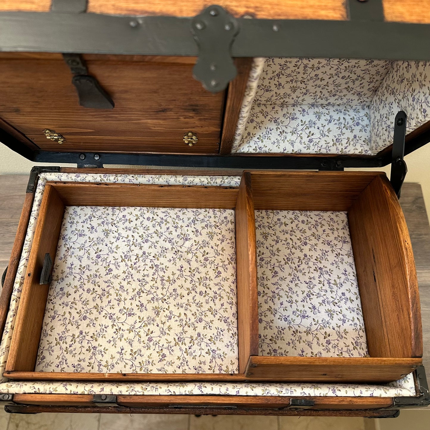 Wooden trunk with floral interior lining on a wooden floor