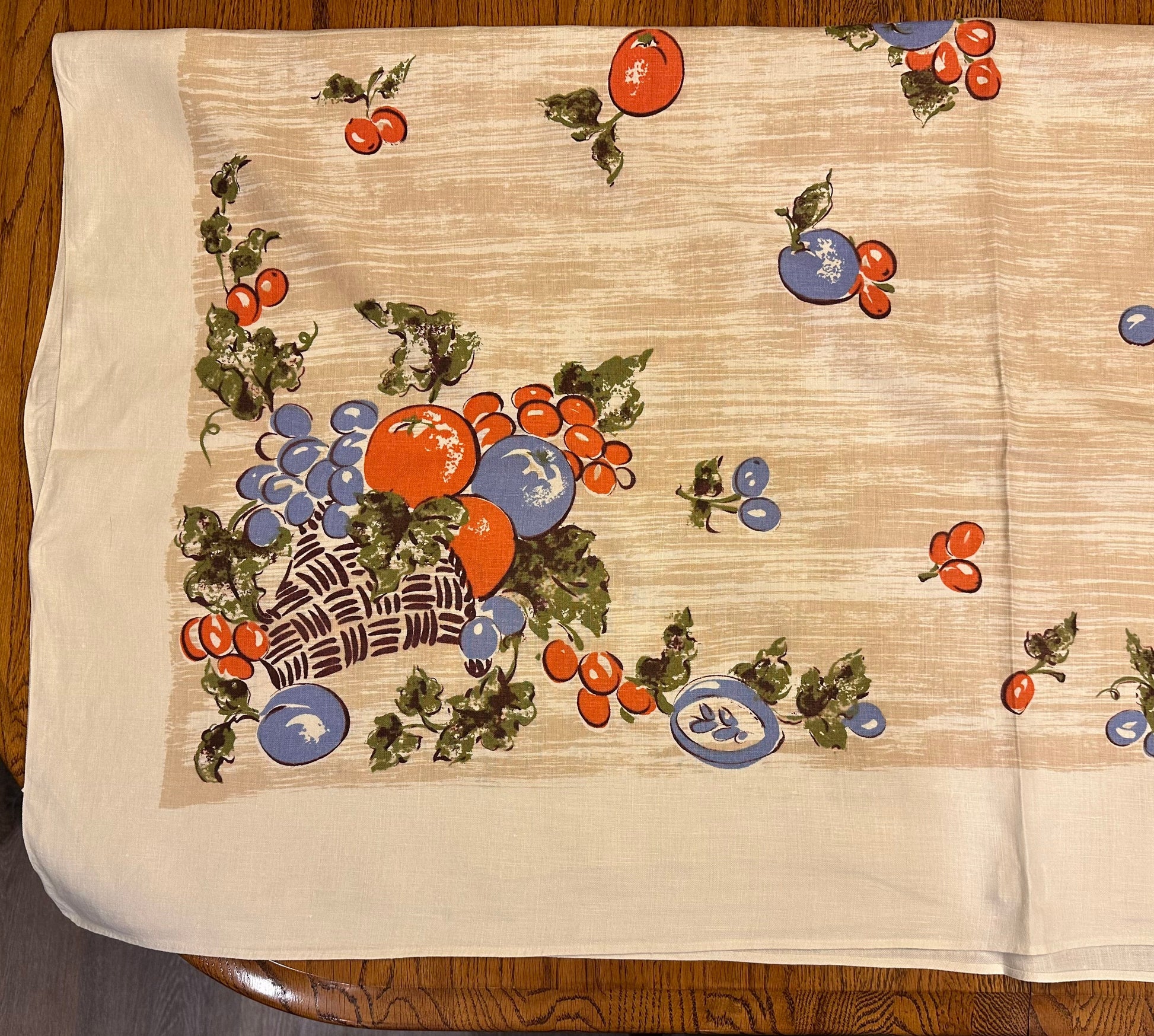 Decorative tablecloth with fruit and floral patterns on a wooden table.