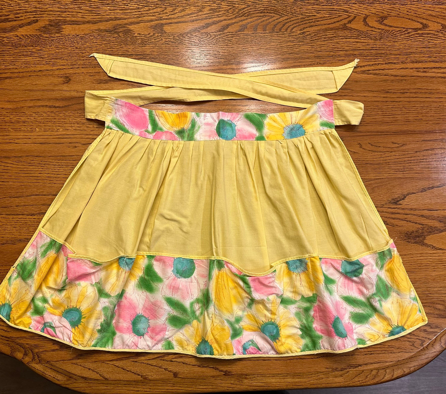Yellow apron with floral pattern on a wooden surface