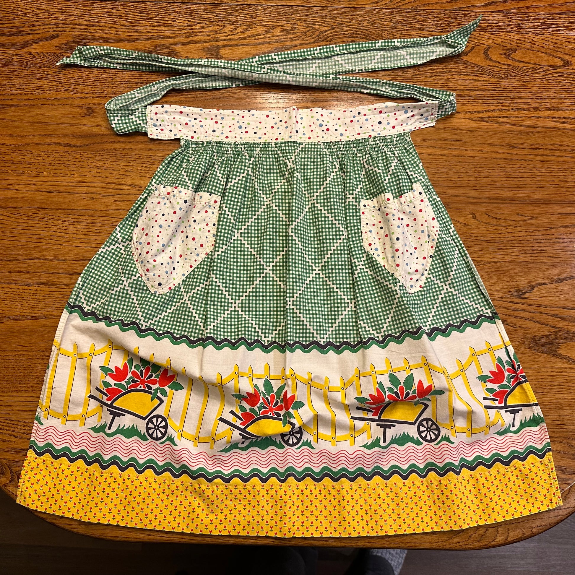 Vintage-style apron with green checkered pattern and floral designs on a wooden surface