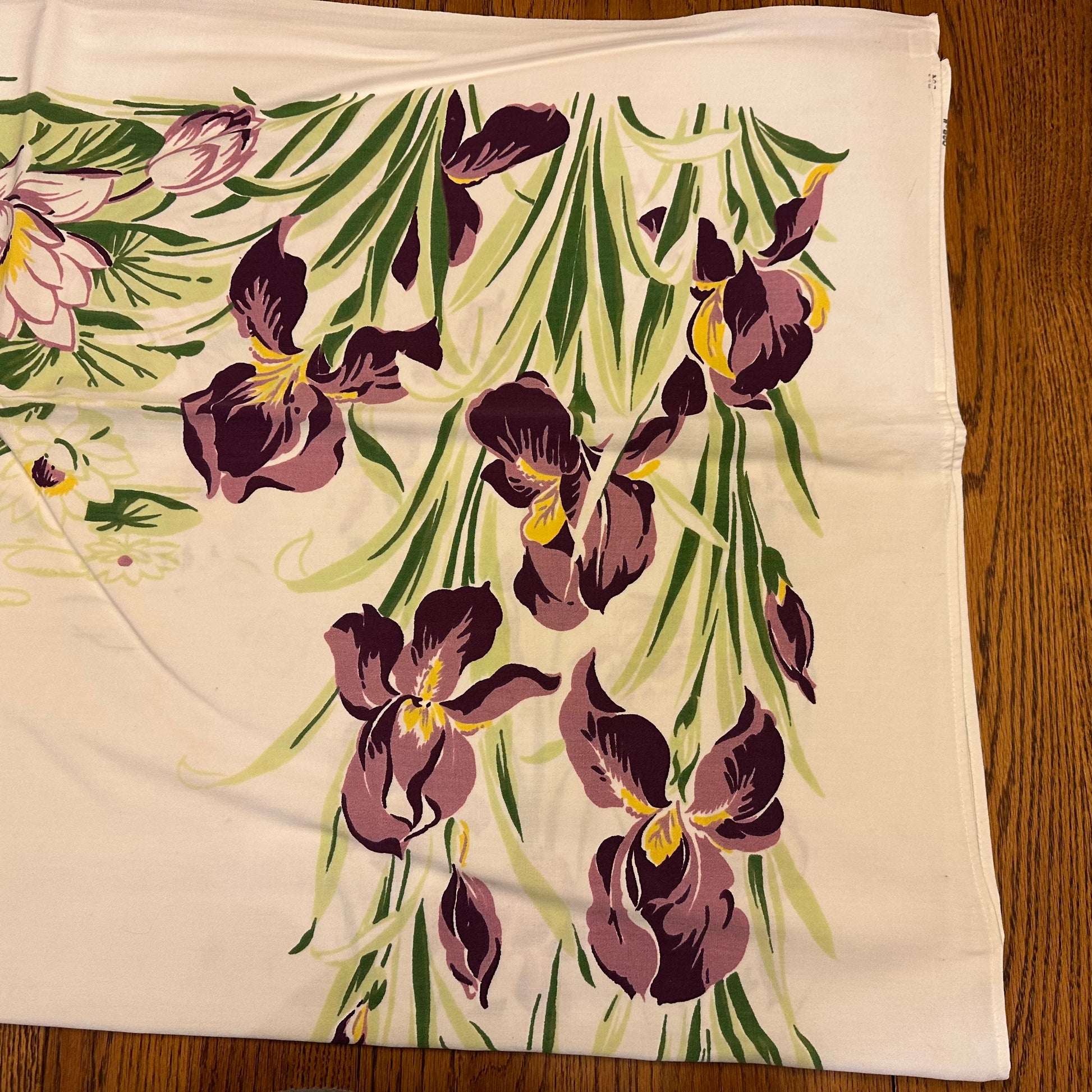 Floral patterned fabric with purple flowers and green leaves on a wooden surface