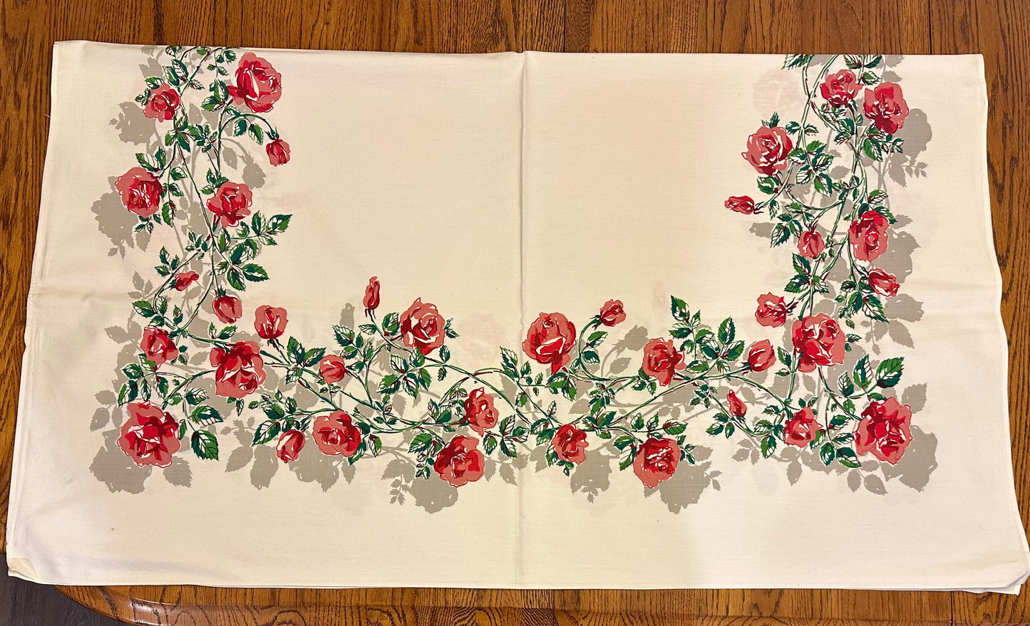 Floral embroidered tablecloth with red roses on a wooden surface