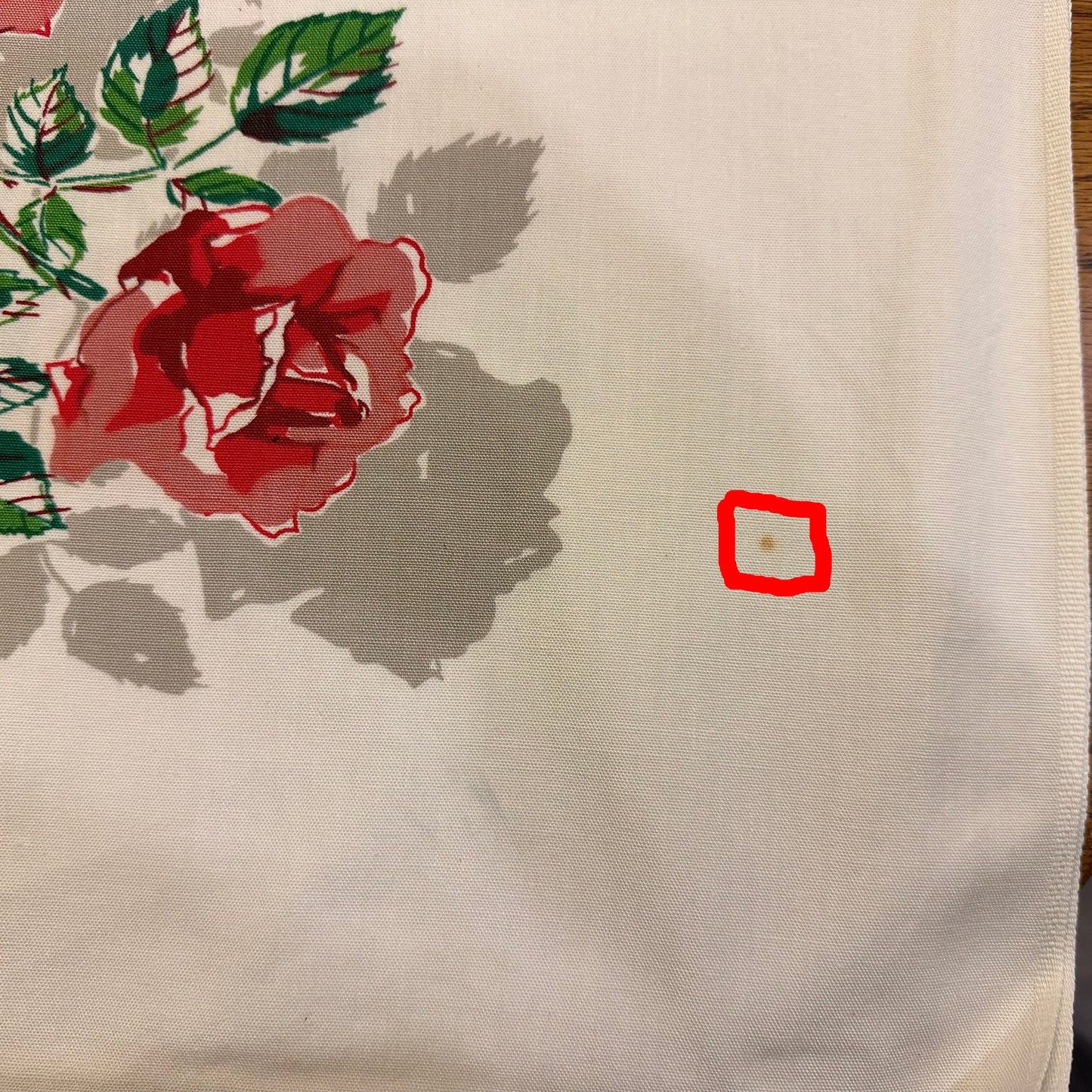 Floral fabric with red rose and green leaves on a beige background