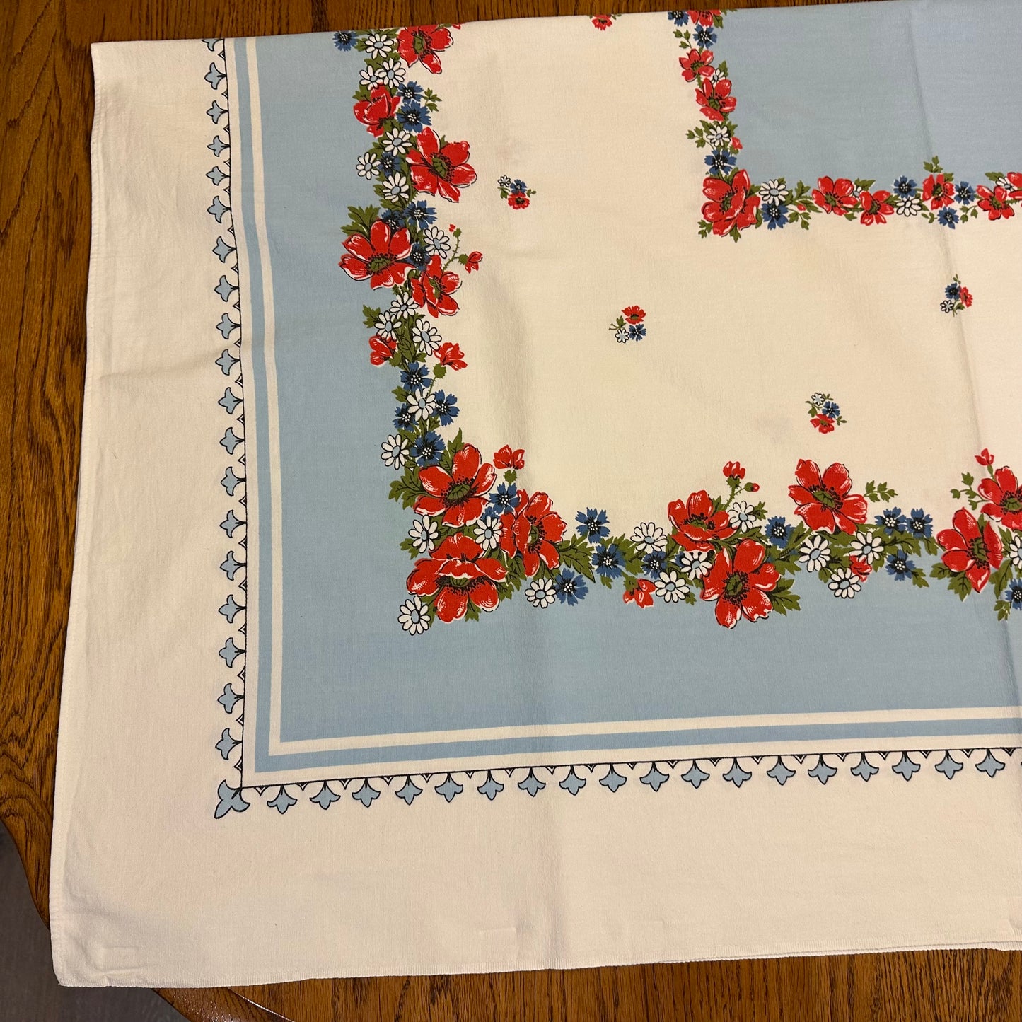 Floral patterned tablecloth with red and blue flowers on a wooden surface