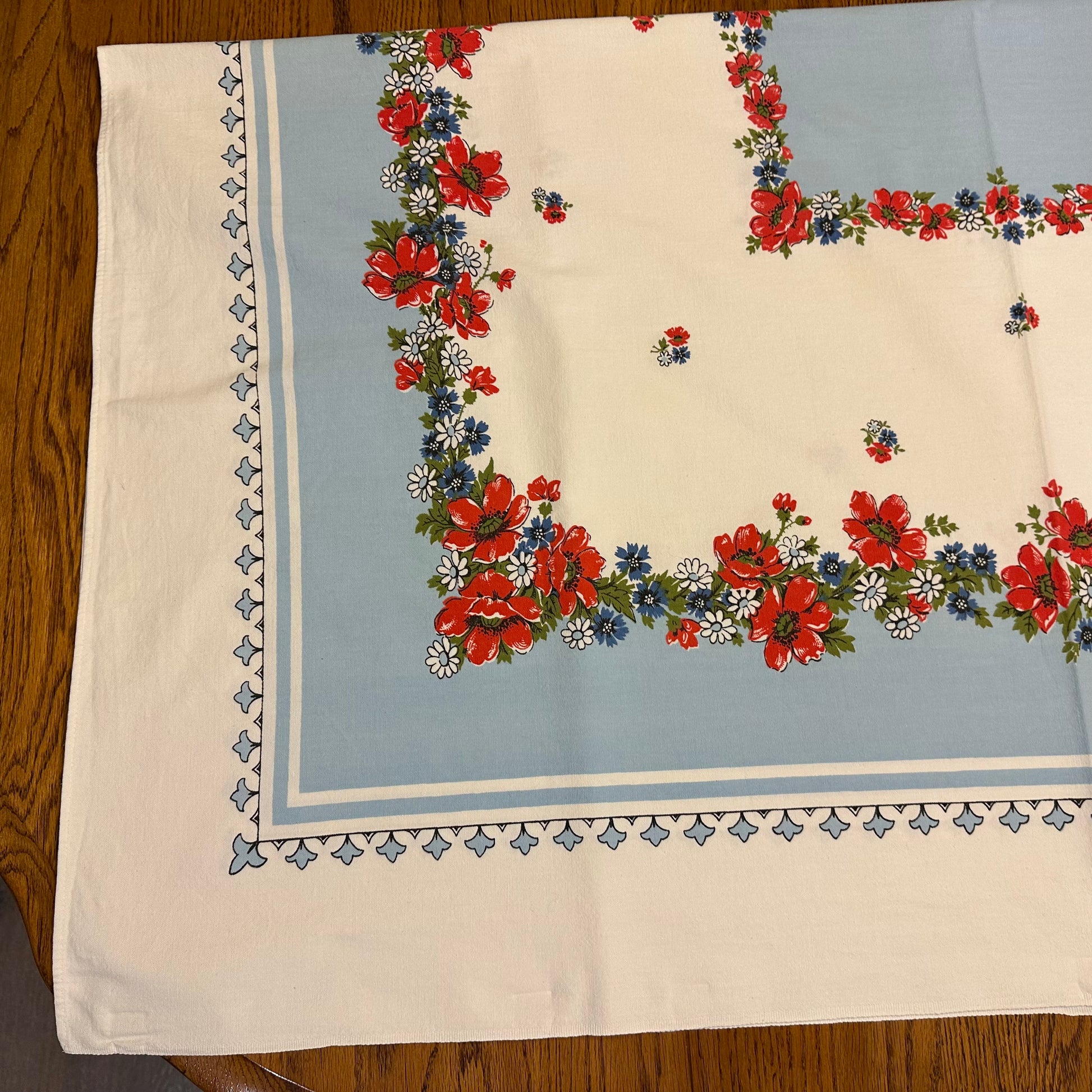 Floral patterned tablecloth with red and blue flowers on a wooden surface