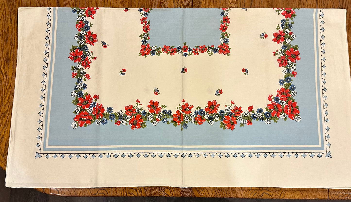 Floral patterned tablecloth with red flowers and blue background on a wooden surface
